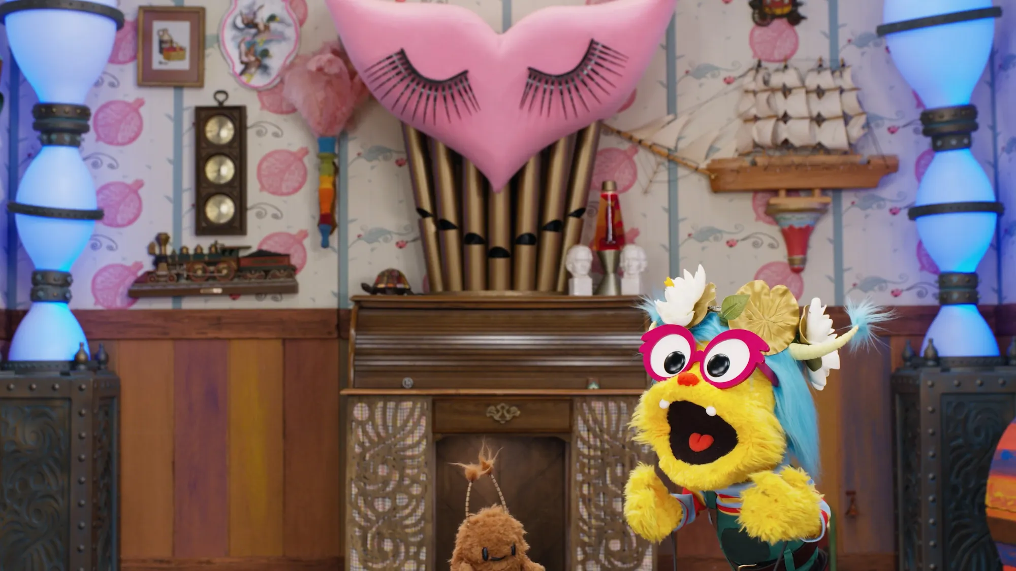 The organ wall on the Albie's Elevator set, flanked by glowing translucent columns, with two puppet characters in the foreground.