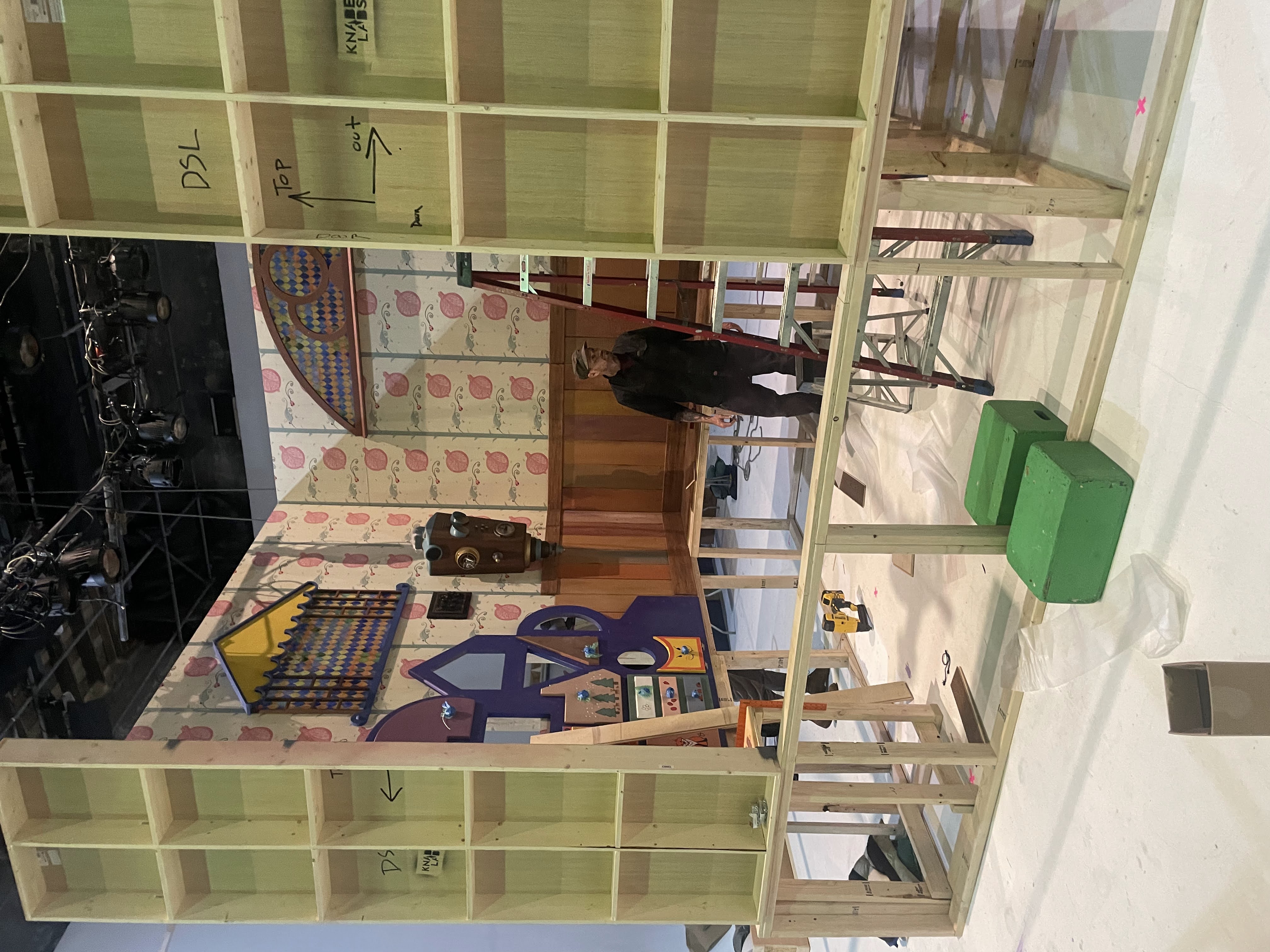 The Albie's Elevator set under construction on the studio stage, showing the raised wooden platform structure and the modular wall framing.